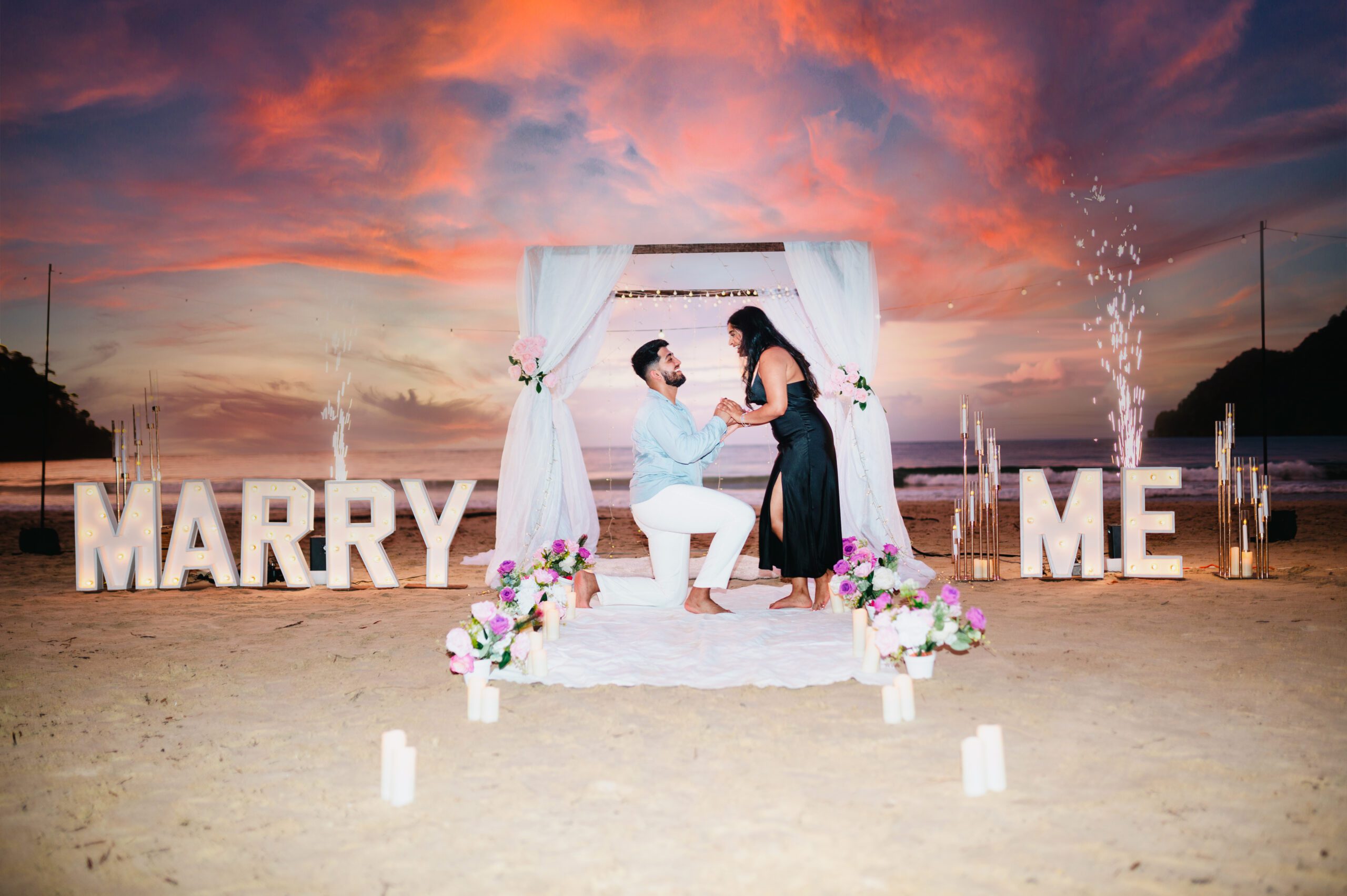 Cold spark machines set up beside romantic floral arch for outdoor marriage proposal in Maracas Beach Trinidad